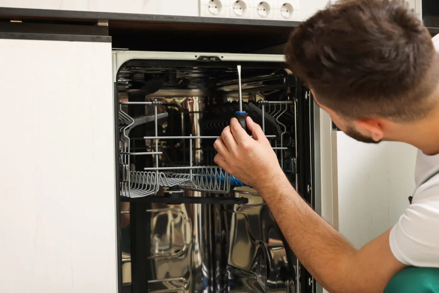 Technician repairing a built-in dishwasher in a Dubai kitchen
