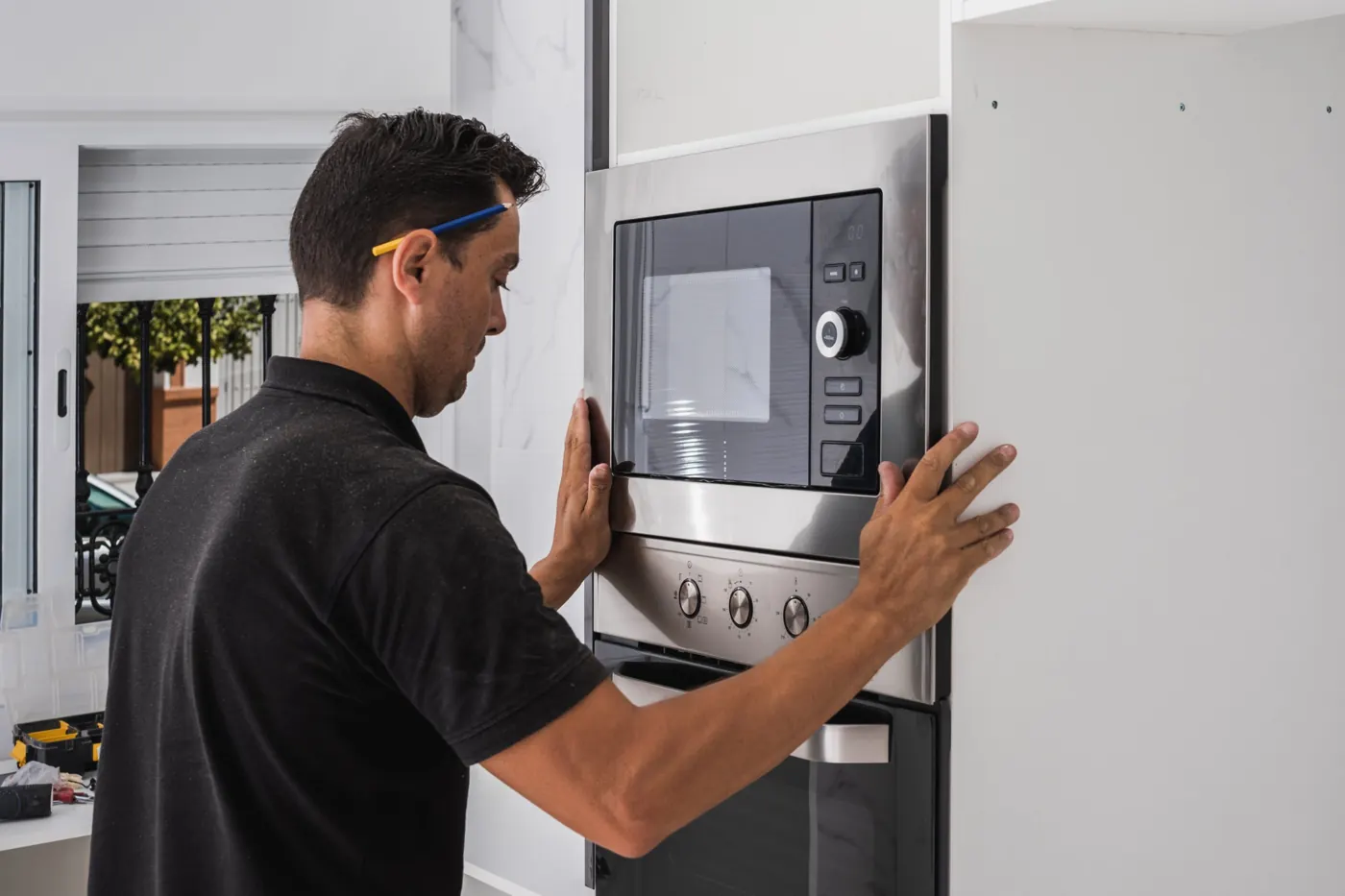 Technician repairing a built-in microwave oven in a Dubai kitchen