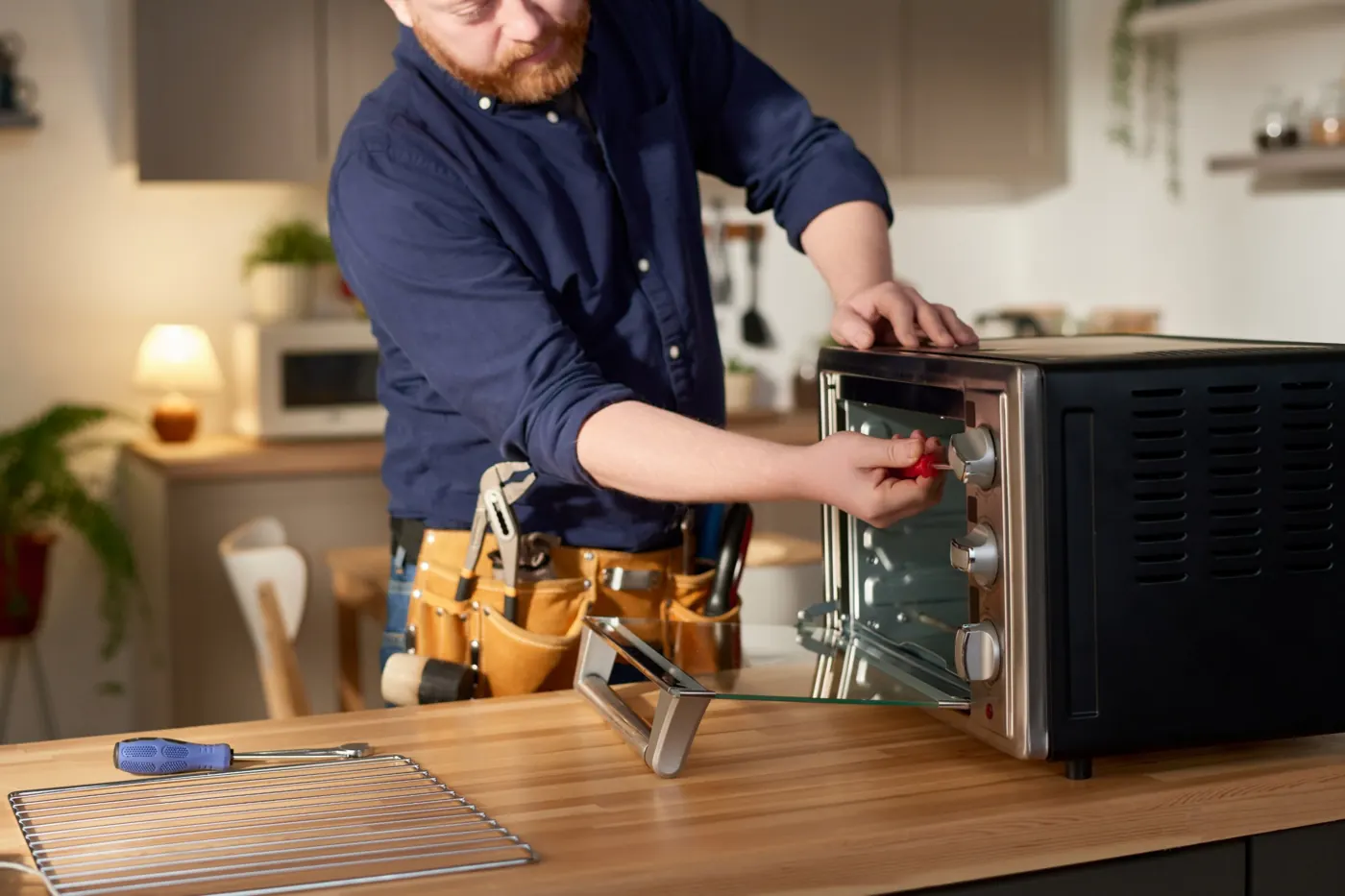 Technician repairing a built-in microwave oven in a Dubai kitchen