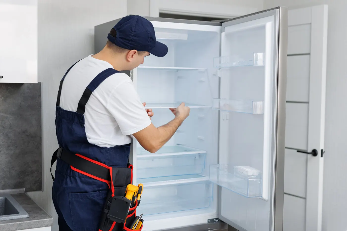Technician checking a refrigerator that is not cooling in a Dubai home
